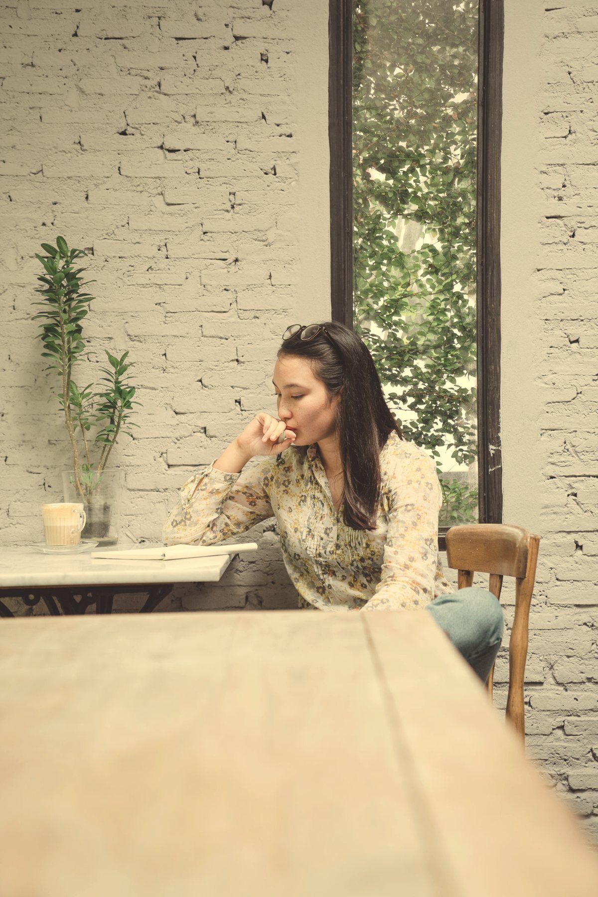 Young Asian woman writing in a journal at a sunlit café table, therapy for life transitions and starting fresh in Ontario