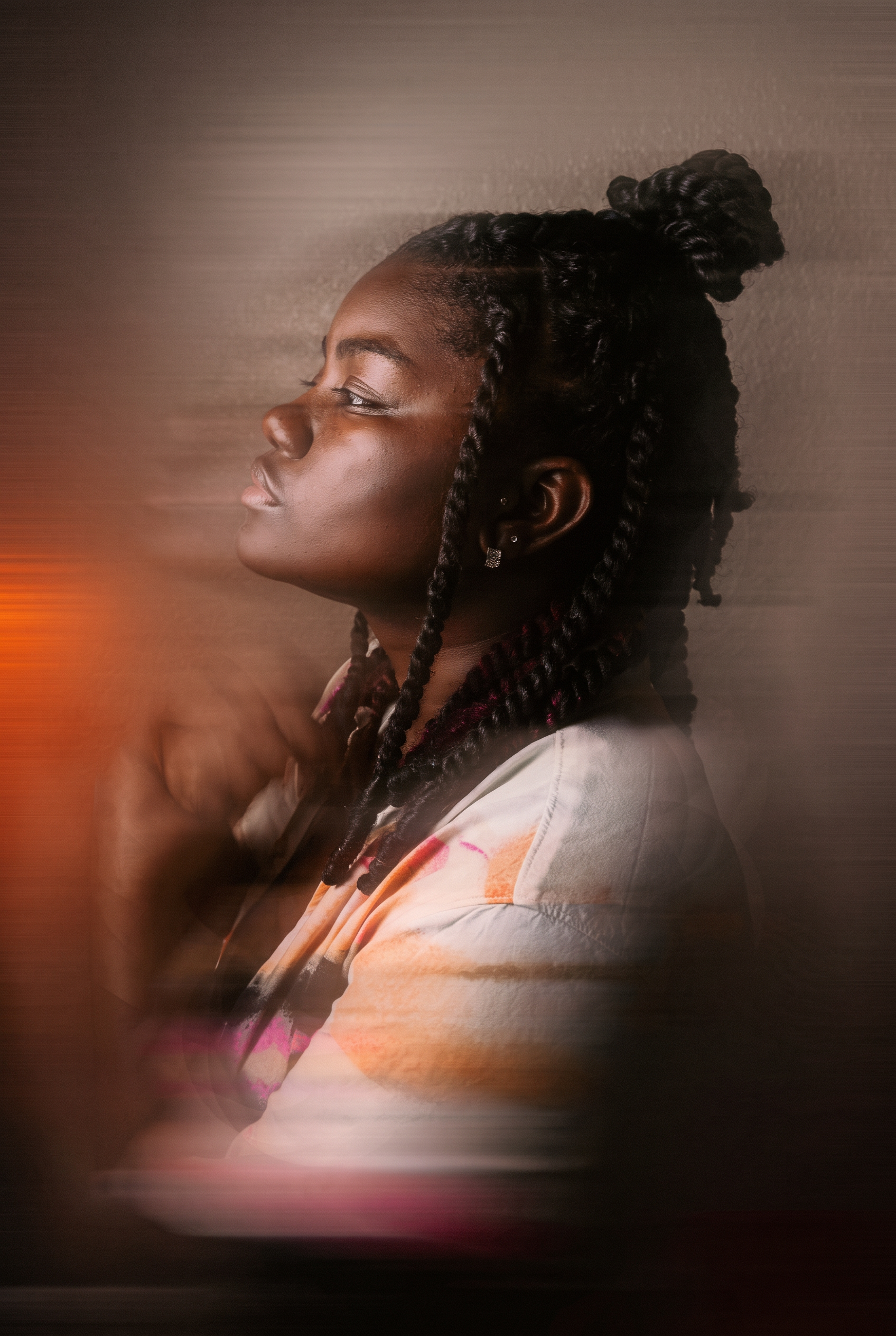 Black woman with braided hair looking upward in a reflective portrait with soft movement, trauma-informed, culturally responsive therapy with Tanika Newman, RSW